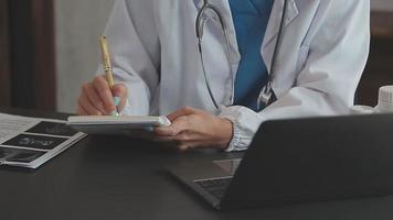 médecin travail avec portable ordinateur et l'écriture sur formalités administratives. hôpital Contexte. video