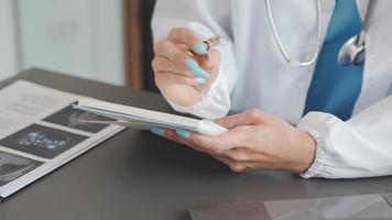 Doctor working with laptop computer and writing on paperwork. Hospital background. video