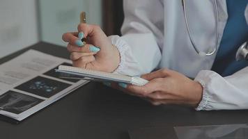 Doctor working with laptop computer and writing on paperwork. Hospital background. video