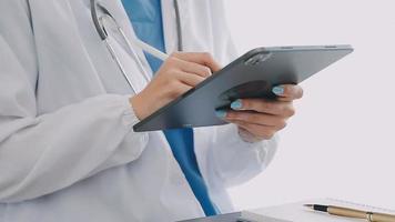 médico trabajando con ordenador portátil computadora y escritura en papeleo. hospital antecedentes. video