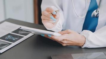 médico trabajando con ordenador portátil computadora y escritura en papeleo. hospital antecedentes. video