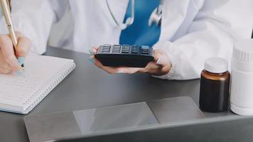 Doctor working with laptop computer and writing on paperwork. Hospital background. video