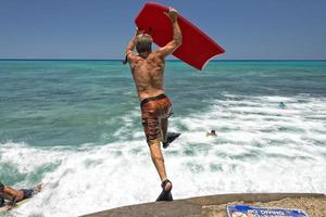 man jumping from pier with body surf photo