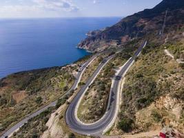 aerial shot of cars passing through a spiral road surrounded by trees in the countryside photo