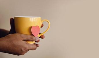 Tea Lover Concept. Hand Holding a Cup of Tea. Eco-Friendly Style Tag made as Heart Shape and Hanging on Cup. Green, Oolong, Fermented, Organic, Healthy and Aromatic Tea photo