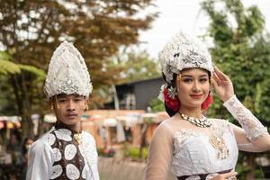 a pair of brides in white clothes standing together very intimately in a tourist park photo