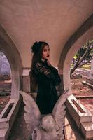 un asiático mujer vestido todas en negro y un de miedo cara estaba en pie terminado el cementerio foto