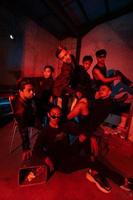 a group of Asian teenagers in black clothes posing very naughty with their friends in a warehouse with a red light photo