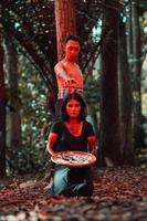 an Asian woman and man were standing in front of a tree while hunting an animal in the middle of the forest until they were covered in blood photo