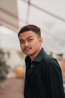 an Asian man with a handsome face and mustache wearing a black shirt while relaxing photo