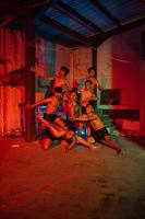 a group of men without clothes dancing poses in an old building with a red light photo