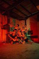 a group of men without clothes dancing poses in an old building with a red light photo