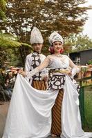 a pair of brides in white clothes standing together very intimately in a tourist park photo