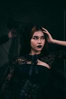 an Asian teenager has a scary appearance with all-black makeup and a black dress like a witch before Halloween photo