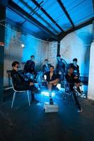 a group of Asian teenagers in black clothes sitting together in a black building with a blue light on the room photo