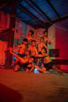 a group of men without clothes dancing poses in an old building with a red light photo