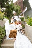 a couple of brides in white clothes were sitting on the stairs with a cheerful faces and full of affection in the middle of the garden photo