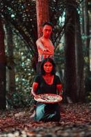 an Asian woman and man were standing in front of a tree while hunting an animal in the middle of the forest until they were covered in blood photo