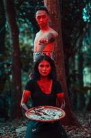 a couple of serial killers have bodies covered in blood and are performing a satanic ritual in the middle of a forest photo