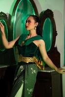 an Indonesian female dancer in an green costume dances in front of a dressing table very beautifully and gracefully photo