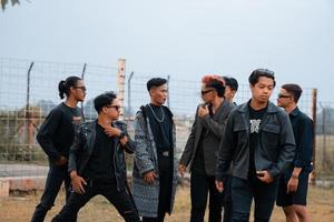 a group of teenage boys in black clothes posing very gallantly with their friends in a field photo