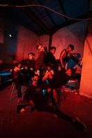 a group of Asian teenagers in black clothes posing very naughty with their friends in a warehouse with a red light photo