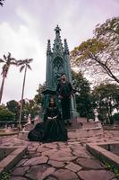 a couple sitting and standing in front of a funeral monument when visiting a friend who has died with a sad expression photo