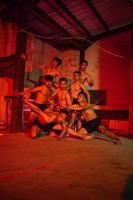 a group of men without clothes dancing poses in an old building with a red light photo