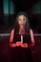 a woman worshiping satan holding a candle in her hand when a ritual is going to be held at a cemetery photo