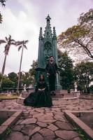 a couple sitting and standing in front of a funeral monument when visiting a friend who has died with a sad expression photo