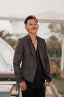 a grown man in a gray suit posing around a cafe table in a very manly and masculine manner before entering the office photo