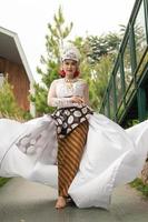 a bride in a white dress is standing in the middle of the bridge with her face full of makeup and a white cloth floating in the air photo