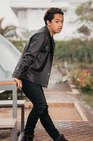 an Asian man is standing beside a cafe table in black leather clothes photo