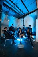 a group of Asian teenagers in black clothes sitting together in a black building with a blue light on the room photo