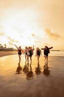 un grupo de asiático adolescentes en camisas corriendo con su amigos con muy alegre expresiones en el playa foto