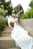 a couple of brides in white clothes were sitting on the stairs with a cheerful faces and full of affection in the middle of the garden photo