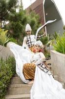 a couple of brides in white clothes were sitting on the stairs with a cheerful faces and full of affection in the middle of the garden photo