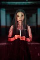 a woman worshiping satan holding a candle in her hand when a ritual is going to be held at a cemetery photo