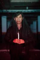 a male devil worshiper with a transparent veil is performing a spooky ritual by holding a candle in his hand photo