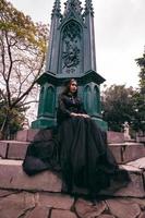 an Asian woman dressed all in black was sitting in a cemetery with a very scary expression while attending the death of her brother photo