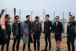 un grupo de Adolescente Niños en negro ropa posando muy gallardamente con su amigos en un campo foto