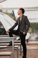 a grown man in a gray suit posing around a cafe table in a very manly and masculine manner before entering the office photo