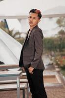 a grown man in a gray suit posing around a cafe table in a very manly and masculine manner before entering the office photo