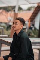 an Asian man with a handsome face and mustache wearing a black shirt while relaxing photo