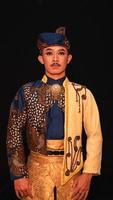 an Asian man wearing a traditional Indonesian dance costume is brown and his face is full of makeup photo