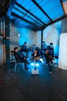 a group of Asian teenagers in black clothes sitting together in a black building with a blue light on the room photo