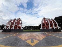 Mataram, Indonesia, February 16, 2023. A gate with the shape of a white traditional house roof and a red cloth motif in Sangkareang Park in the center of Mataram city photo