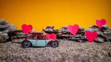 Minahasa, Indonesia  December 2022, toy car with gradient orange background and a heart photo