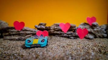 Minahasa, Indonesia  December 2022, toy car with gradient orange background and a heart photo