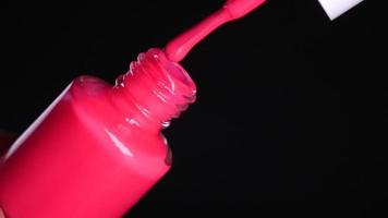 Pink neon nail polish on black background video